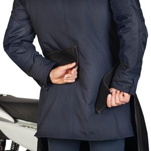 coprigambe da indossare – facile e veloce da mettere tramite tracolla e fasce di regolazione in neoprene sul retro – privo di punti di fissaggio sullo scooter – taglio ergonomico – spacchi laterali per un’ampia libertà di movimento (piede a terra) – costruzione a tre strati: – esterno in tessuto impermeabile – membrana interna impermeabile – imbottitura termica in pile sulle gambe – sistema di ancoraggio al sottosella in caso di parcheggio – pettorina integrata – profilo rifrangente – tasca trasformabile in busta–contenitore di minimo ingombro